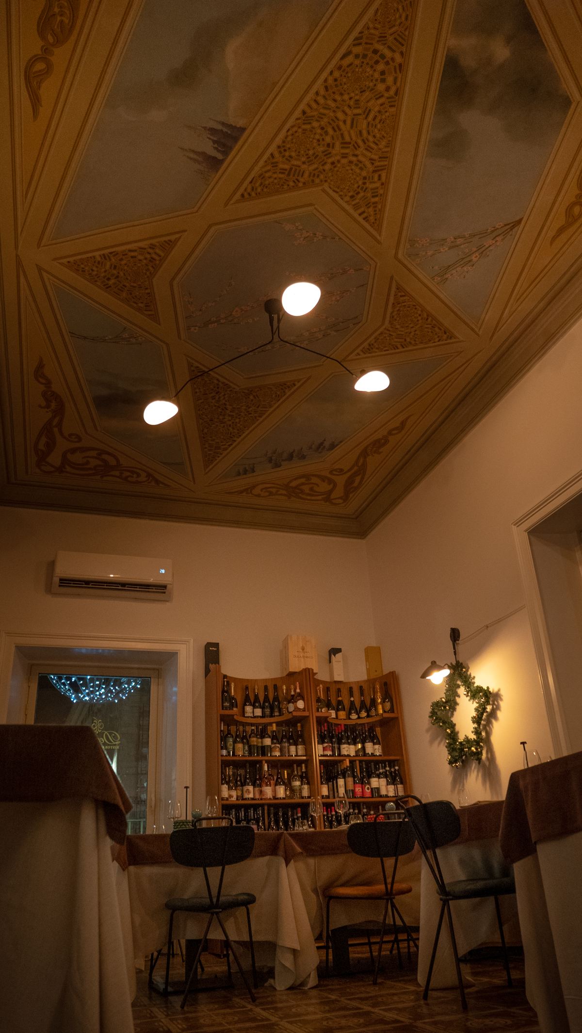 La sala di Decanter a Caltagirone, con il soffitto affrescato e la parete dei vini