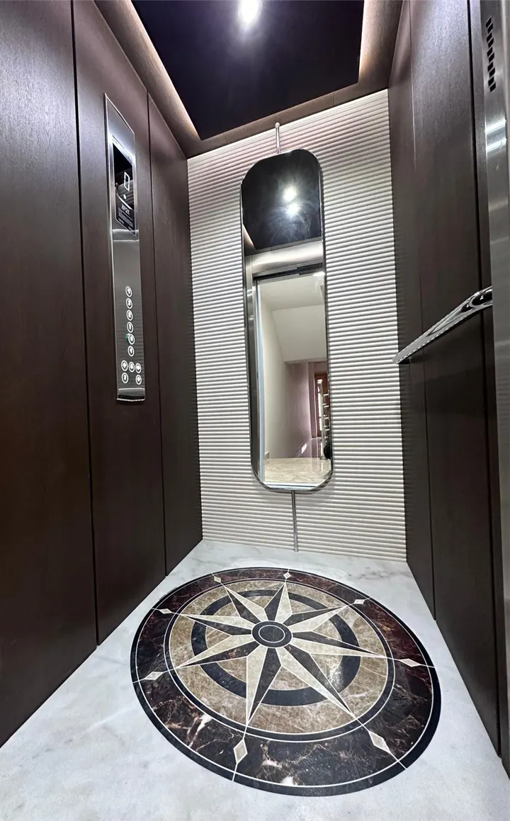 Cabina con pareti scure, specchio e pavimento in marmo con rosa dei venti